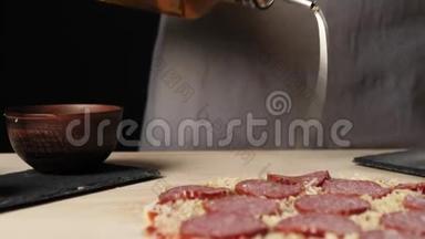 专业厨师用橄榄油喷洒比萨饼，以增强用比萨饼配料装饰的桌子上的风味。 面团的概念